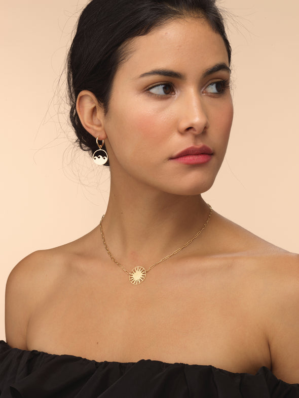Model wearing gold roman sun necklace with think chain. 