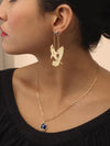 Model wearing gold shark and surfboard earrings. 